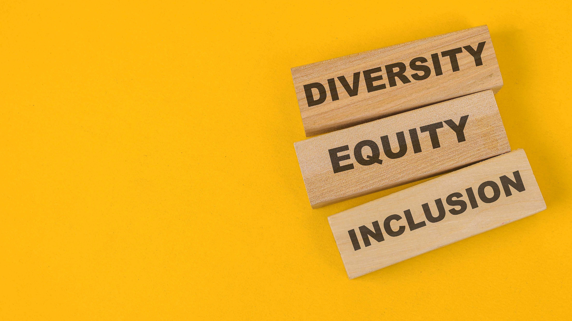 yellow background with wooden blocks that have the words diversity equity and inclusion in black text.