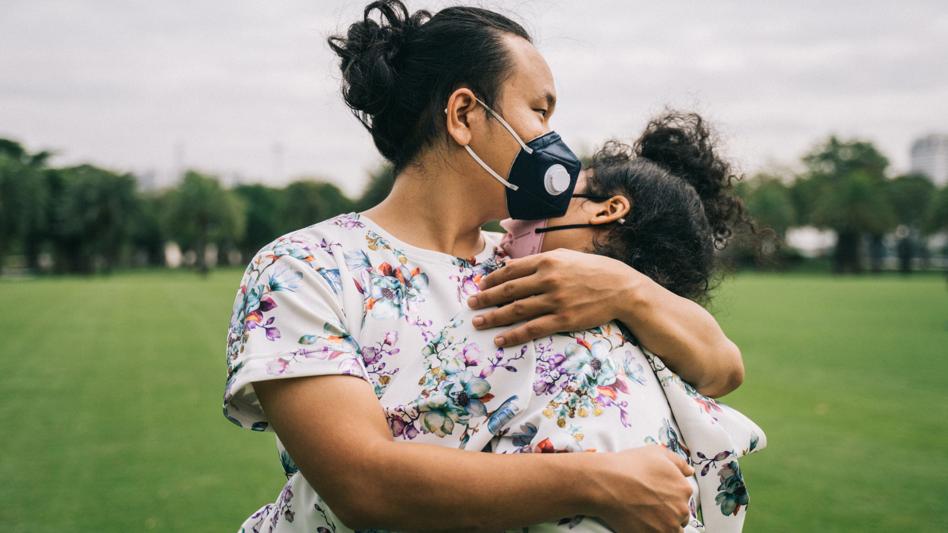mother holding child, both wearing N95 masks