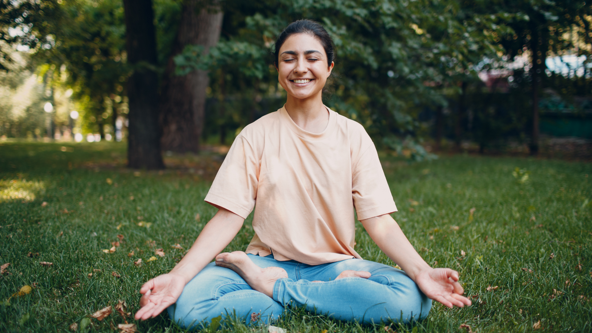 South Asian woman doing yoga on grass