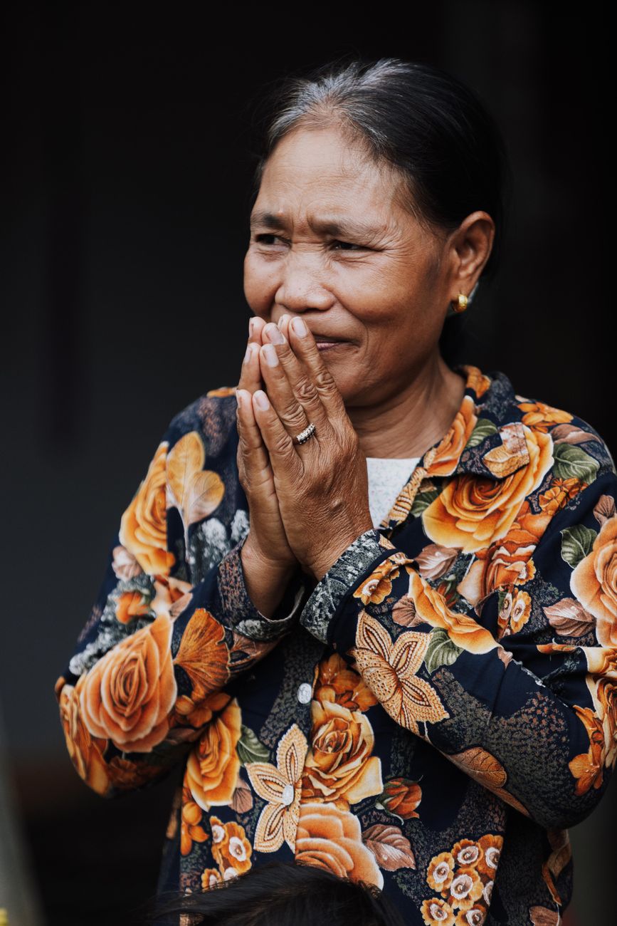 elderly woman with hands clasped in floral shirt