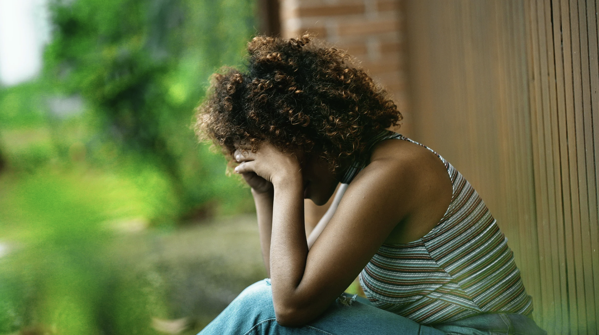 woman with her face in her hands sitting outside